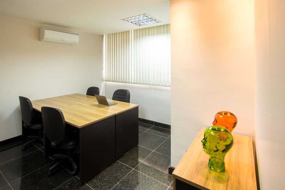 Escritório exclusivo mobiliado, com mesa clara, cadeiras pretas e persianas